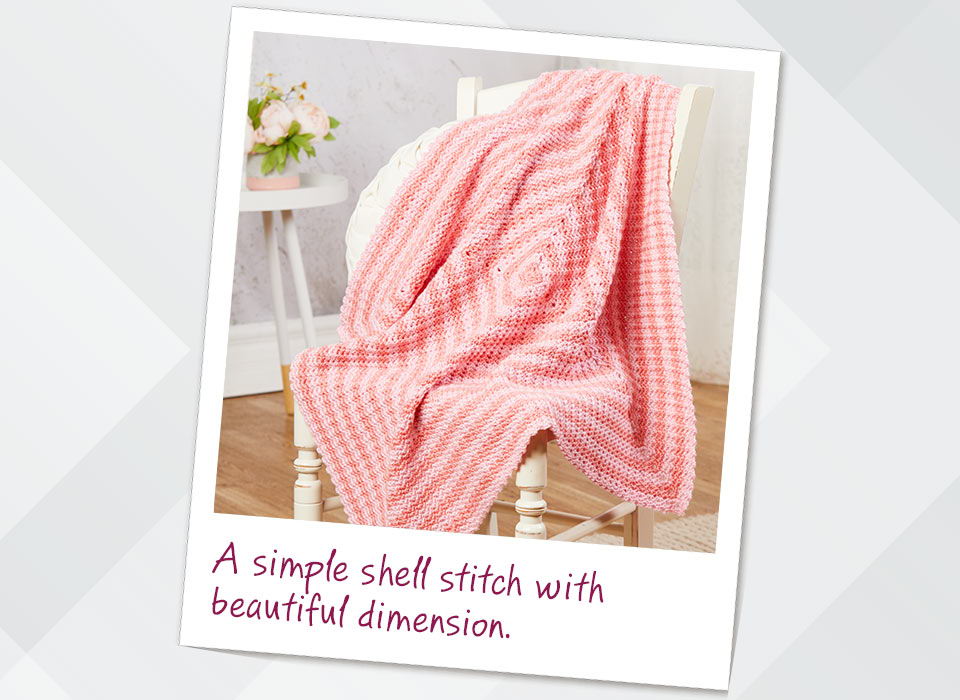 A pink blanket draped over a chair with a textured pattern. A simple shell stitch with beautiful dimension.