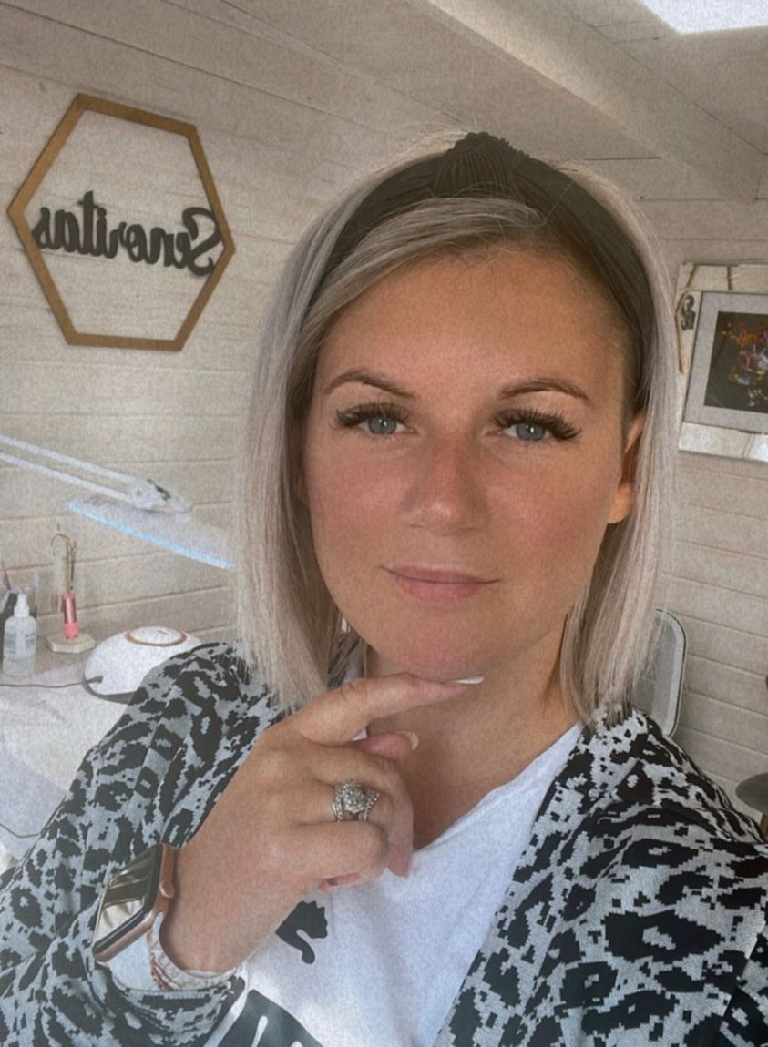 A woman with blonde hair posing thoughtfully in a salon setting.
