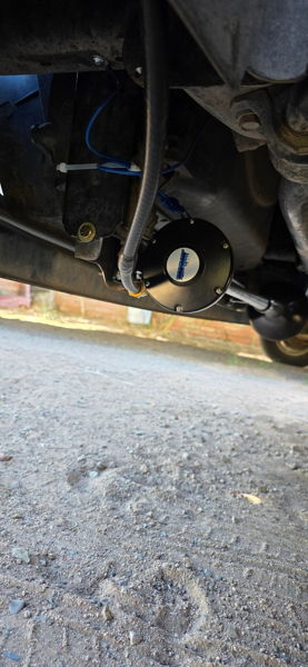 Close-up of black horn solenoid with braided air line and blue wiring mounted under vehicle