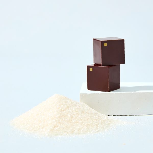 Two brown sugar cubes beside a mound of white sugar.