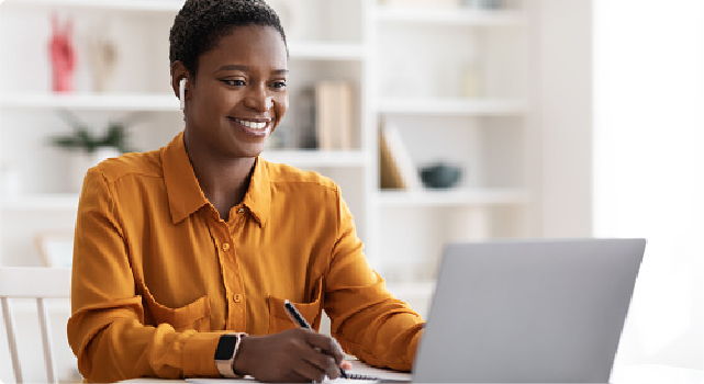 Woman wear earbuds, looking at laptop.