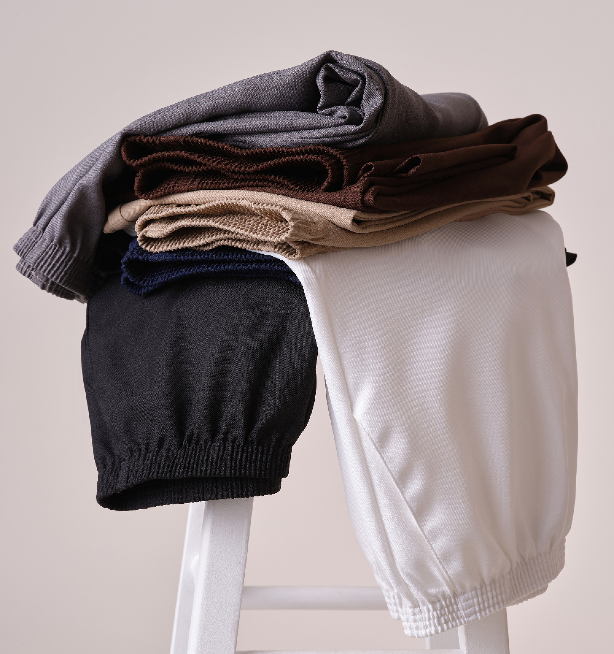 A stack of folded pants on a white chair.