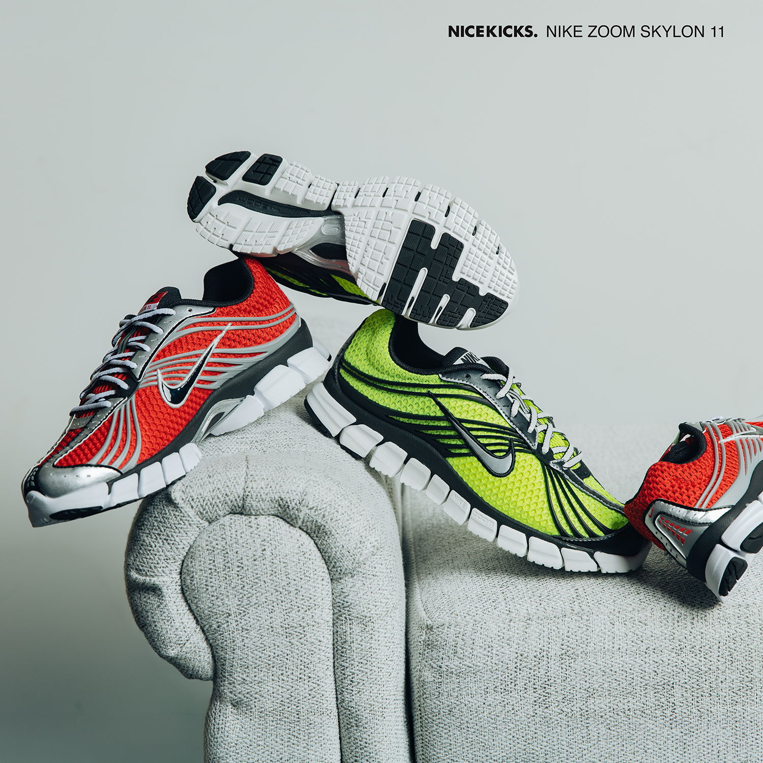 Three colorful Nike shoes displayed on a gray couch.