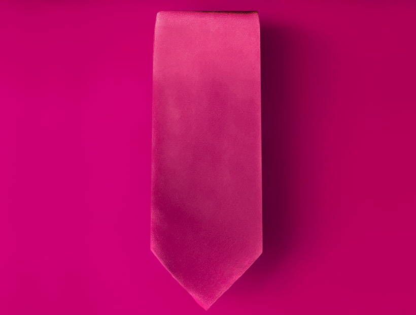 A fuchsia tie folded on a fuchsia background