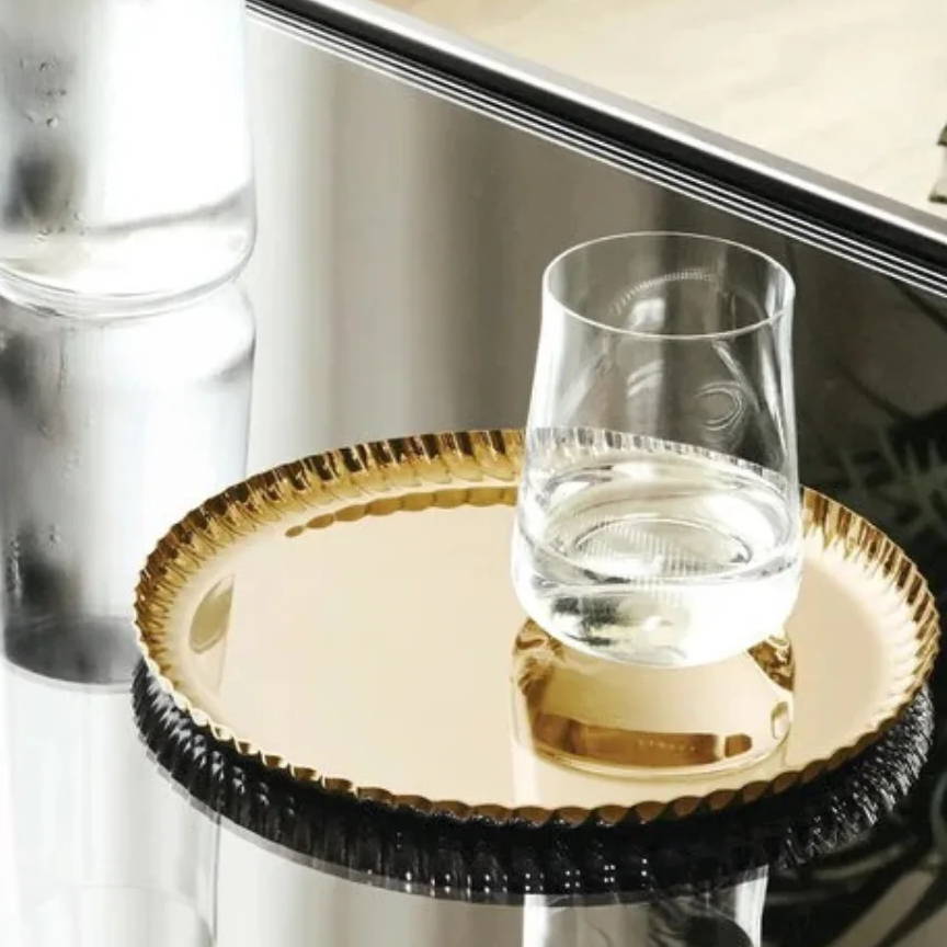 a gold tray with a glass cup on top 