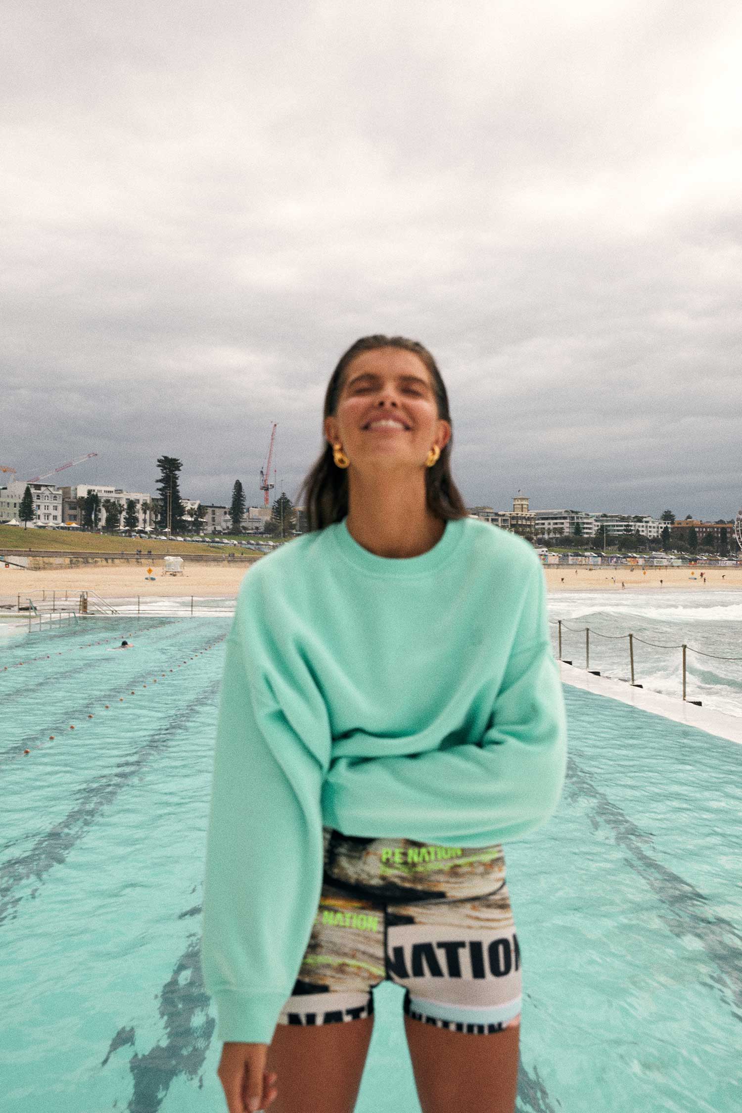 Girl standing next to a pool in a sweater