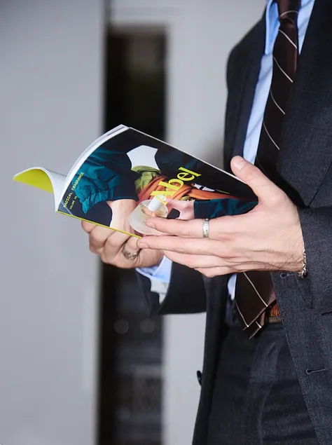A person in a suit holding an open magazine.