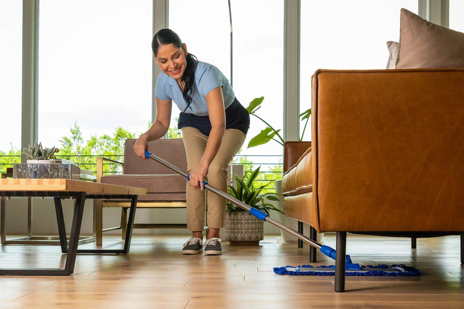 lady mopping underneath sofa using a flat mop