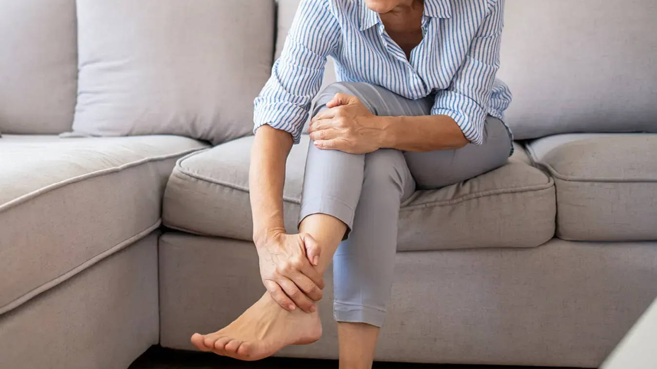 Older woman with arthritis massaging a painful foot. Joint pain. Inflammation.