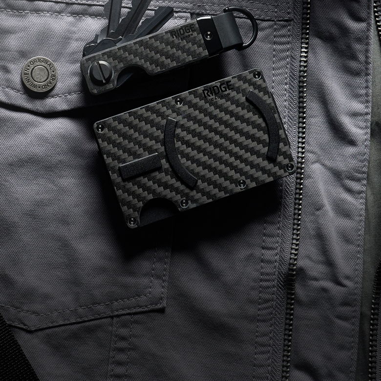 A carbon fiber wallet and keychain on a gray jacket.
