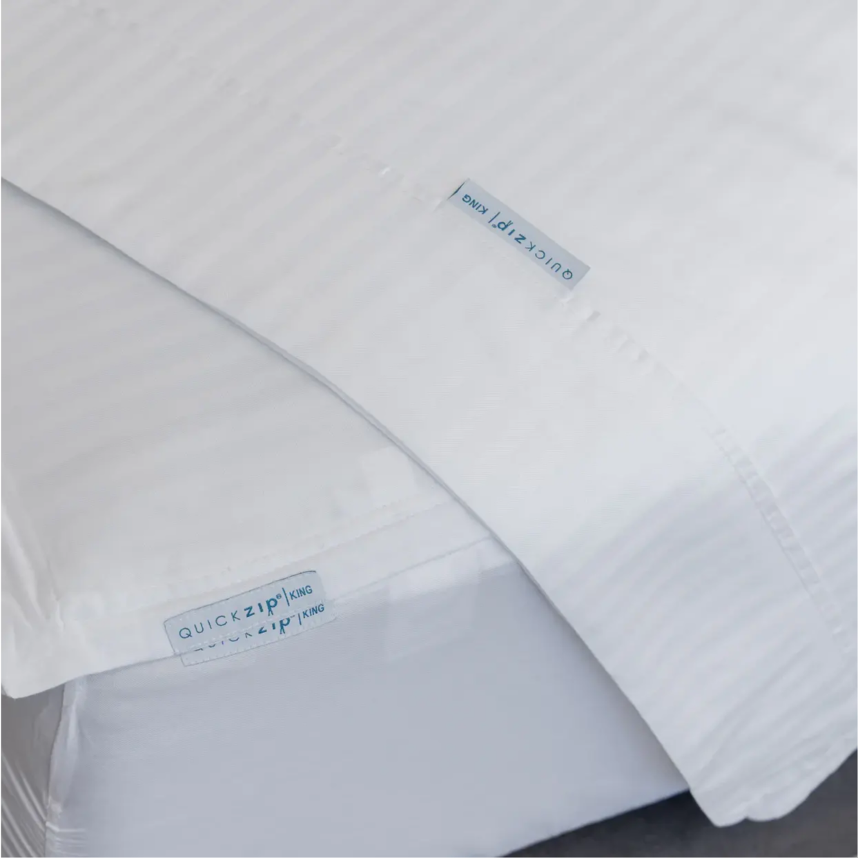 ComfortCore sateen stripe flat sheet laying atop a sateen stripe fitted sheet. 