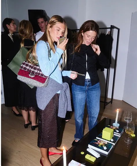 Two women examining items on a table at an event.
