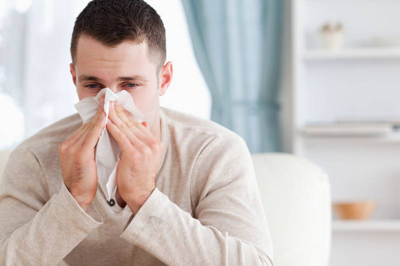 Un uomo si soffia il naso. Il naso che cola è un sintomo comune dell'allergia agli acari della polvere e si manifesta con maggiore frequenza negli ambienti chiusi