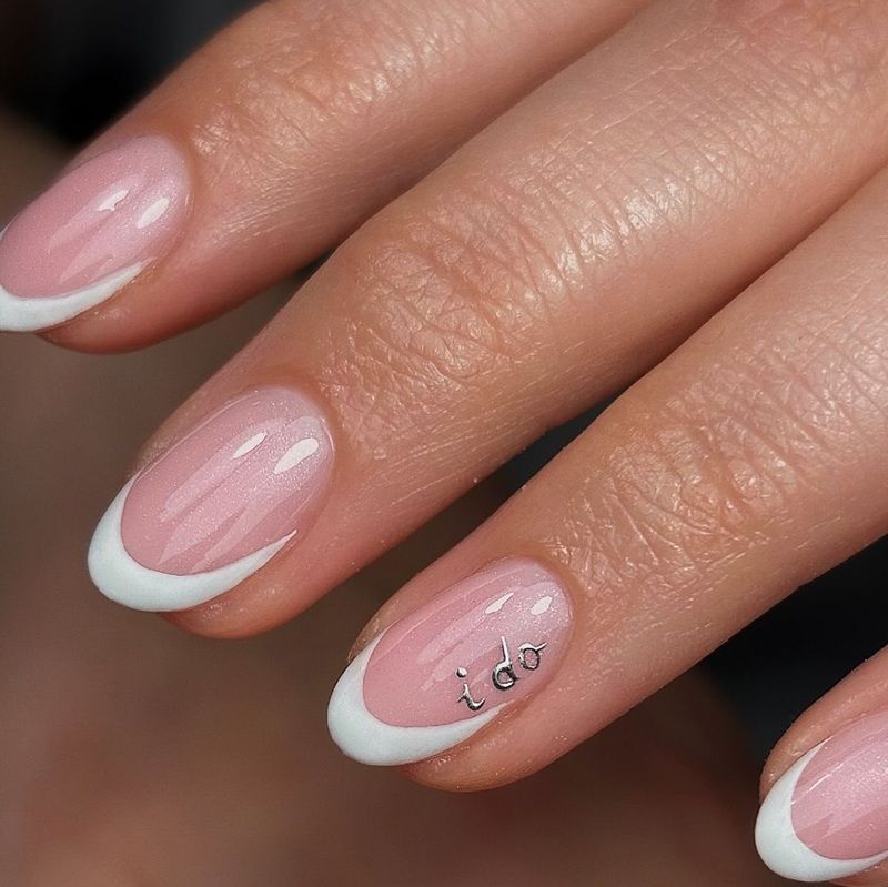 Close-up of a manicured hand with pink and white nails.