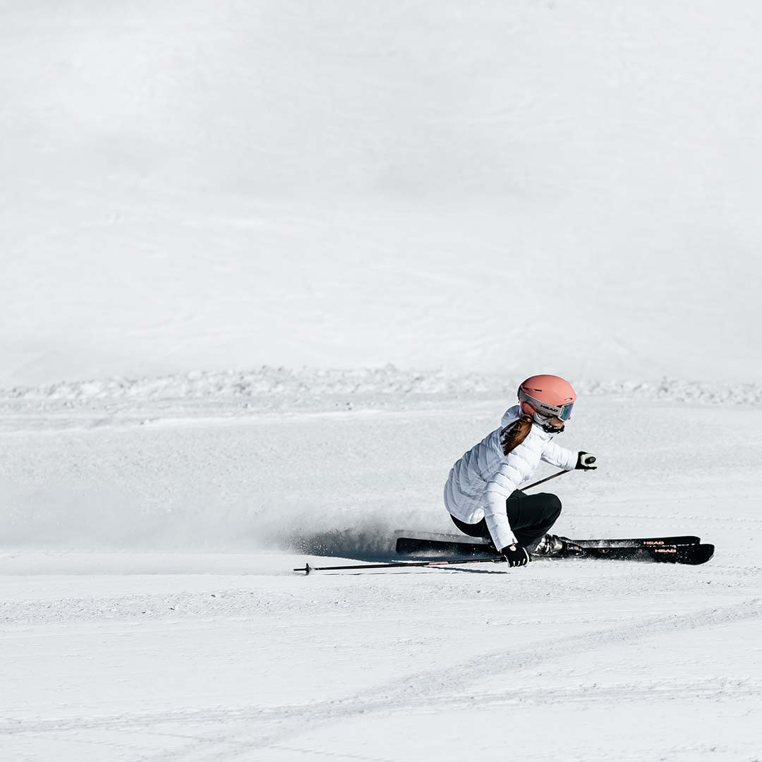 A woman confidently descends a hill on her skis, turning sharply.