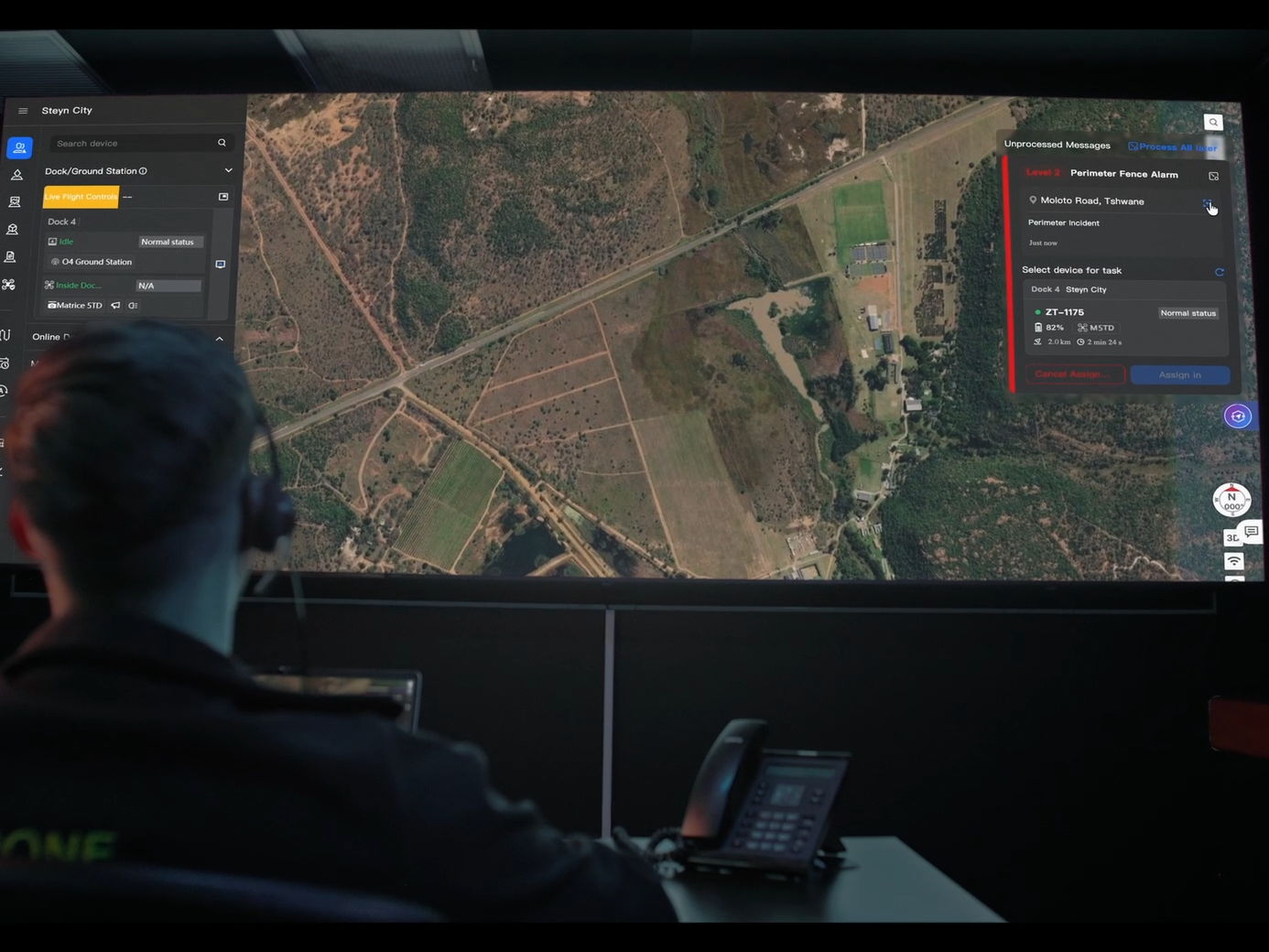 Person monitoring a map on a large screen with control interface.