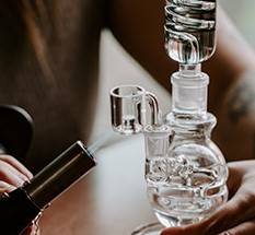 A man using a torch on his glass dab rig