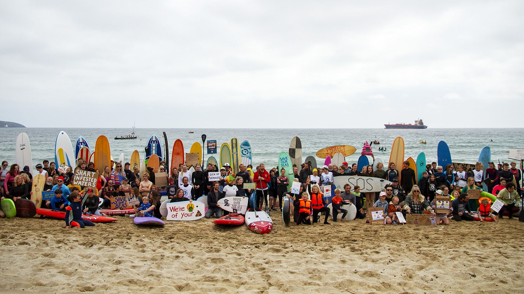 Group of people on a beach with surfboards and colorful inflatables.