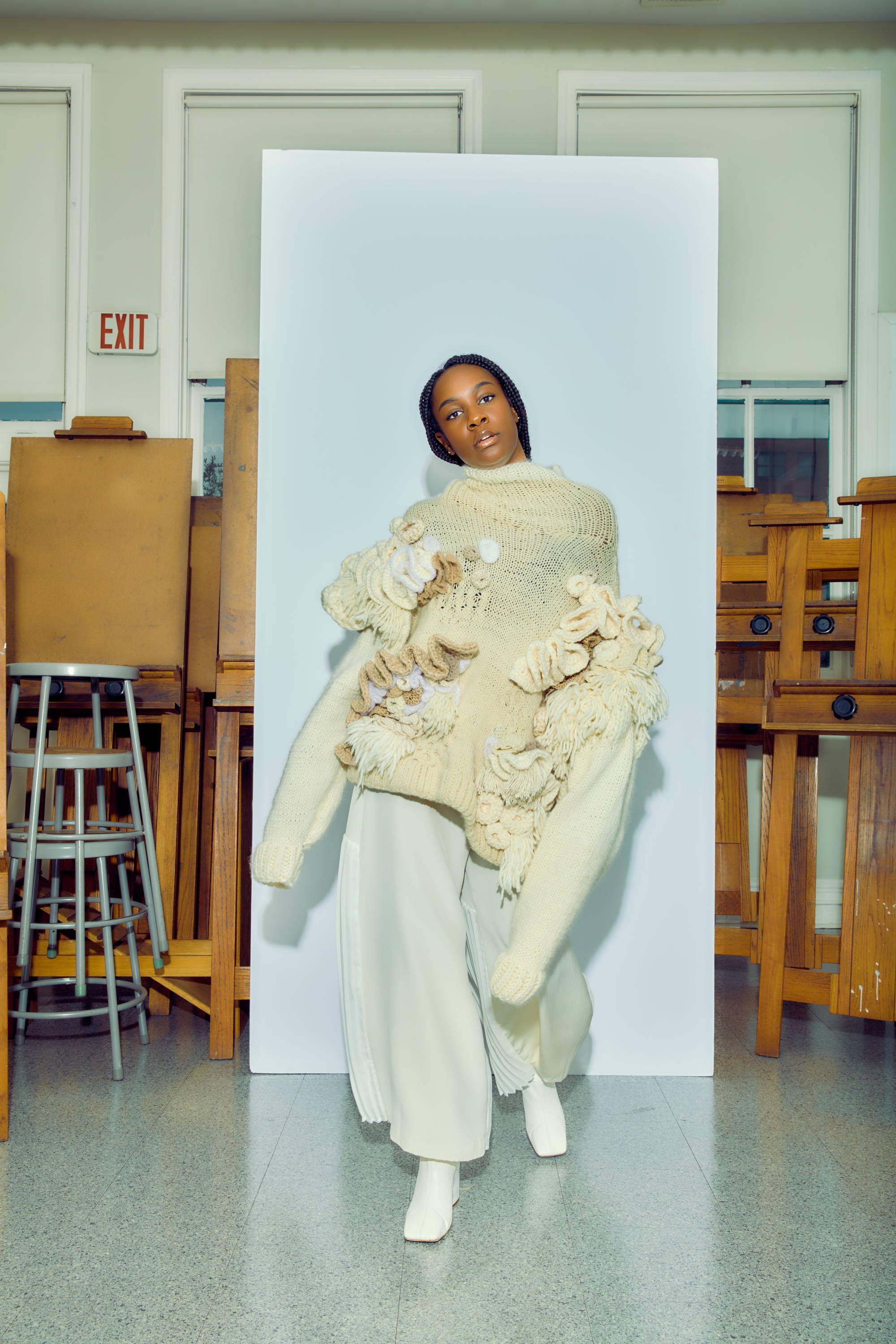 Model in a unique sweater poses in an art studio.