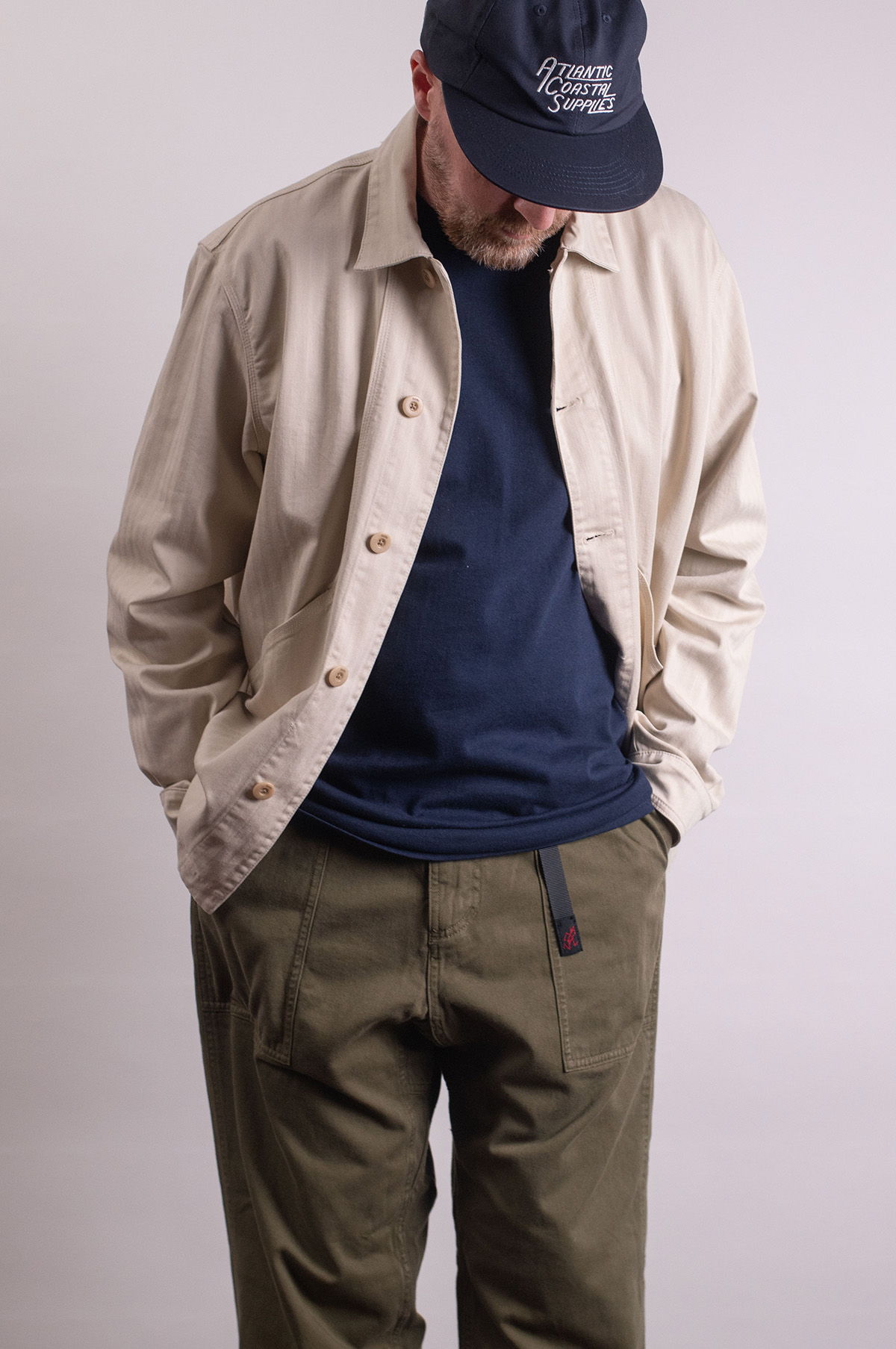 Person wearing a light jacket, blue shirt, and olive green pants.