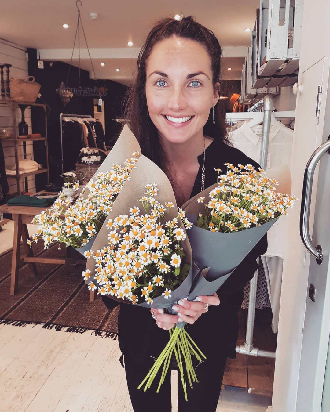 Daisy Caunter holding bunches of daisies at Busby & Fo Totnes store