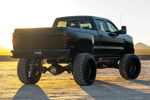 Rear three-quarter sunset view of black lifted Silverado thumbnail