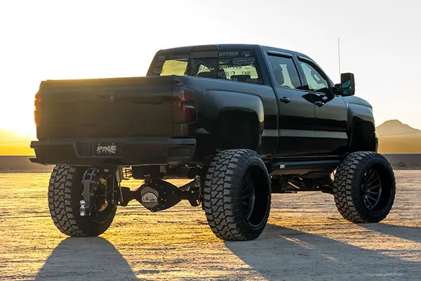 Rear three-quarter sunset view of Elias's black lifted 2015 Chevrolet Silverado 2500HD with large off-road tires, install photo 3