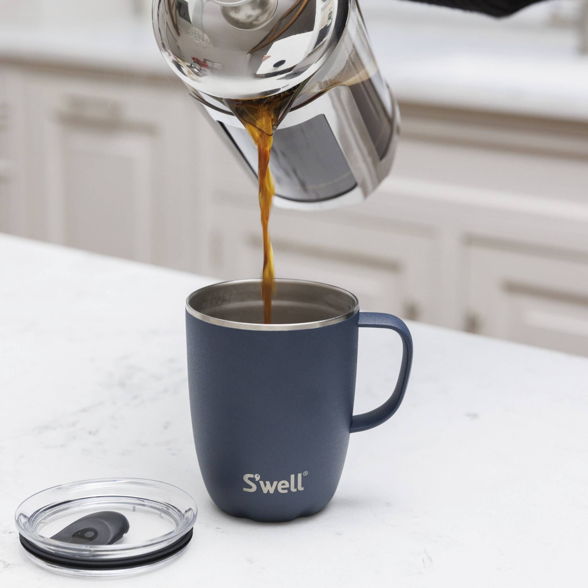 A travel mug with tea being poured into it.