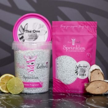 Two containers of sprinkles with pink labels and citrus fruits nearby.