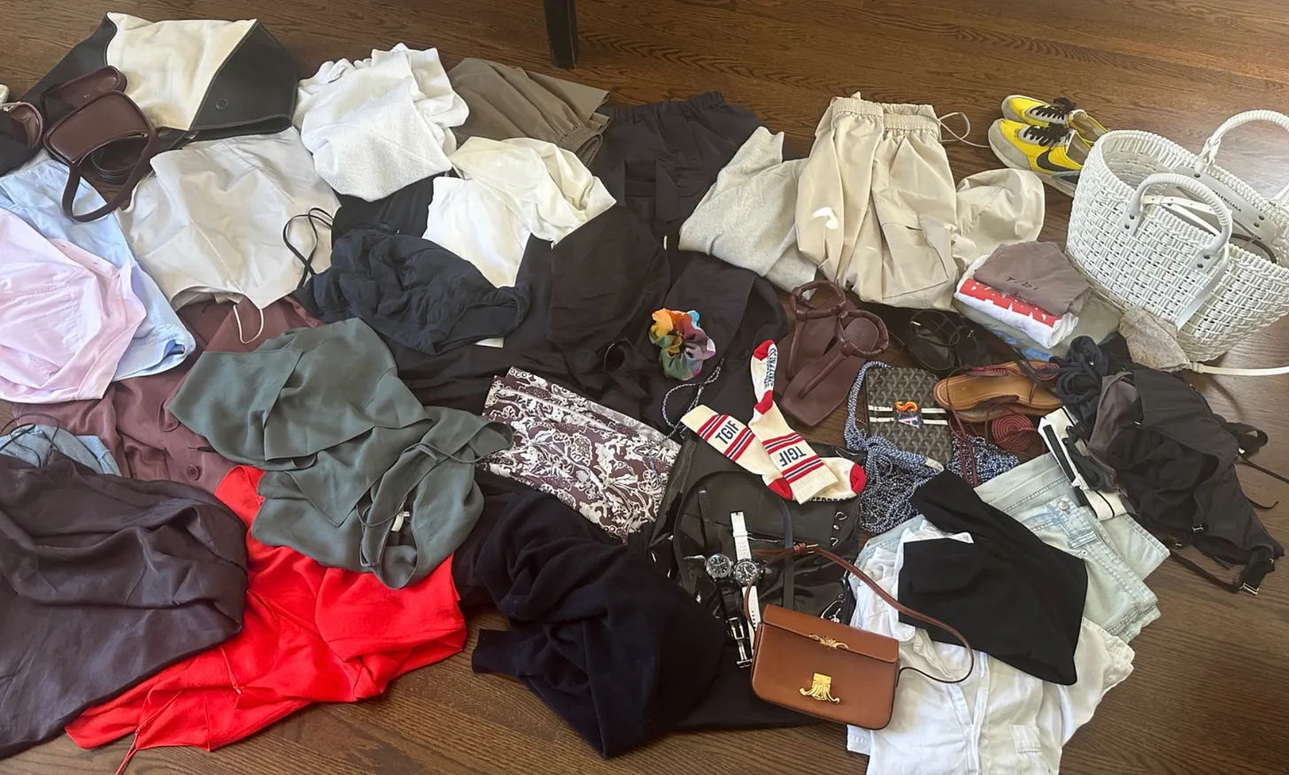 A variety of clothing items scattered on a wooden floor.