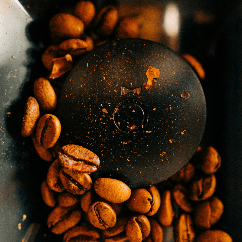 Coffee beans scattered around a black grinder base.