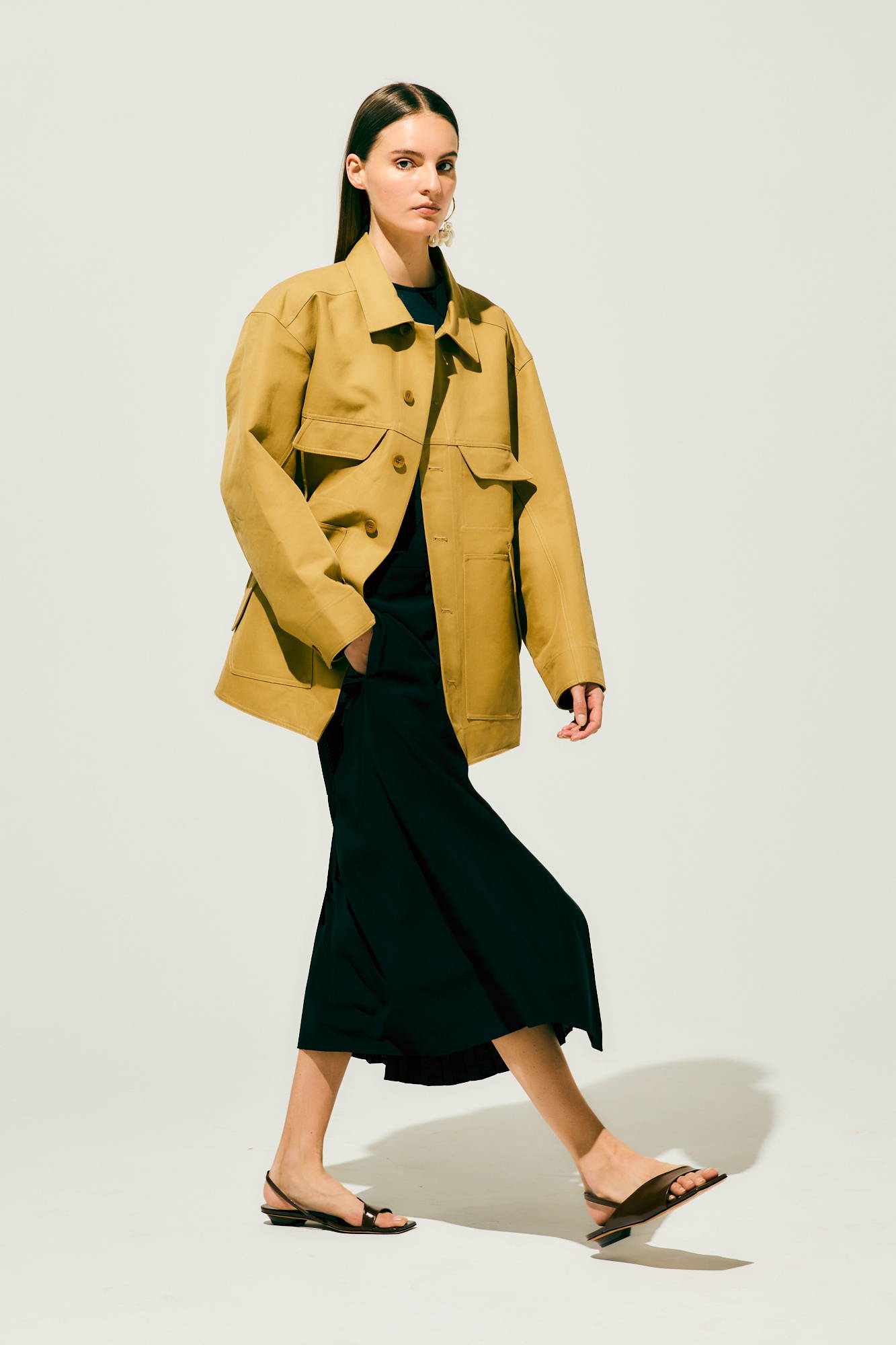 Model walking in a stylish outfit featuring a yellow jacket and black skirt.
