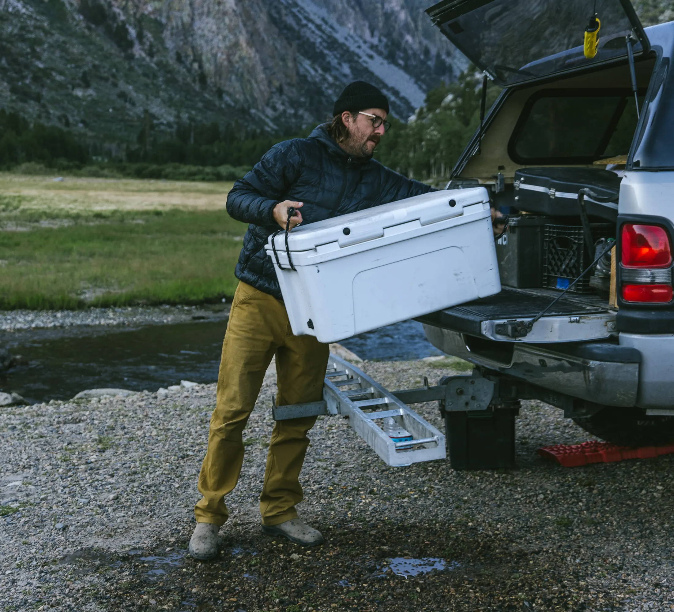 Man unloading cooler from the back of a pickup wearing Cast Iron Sierra Pant