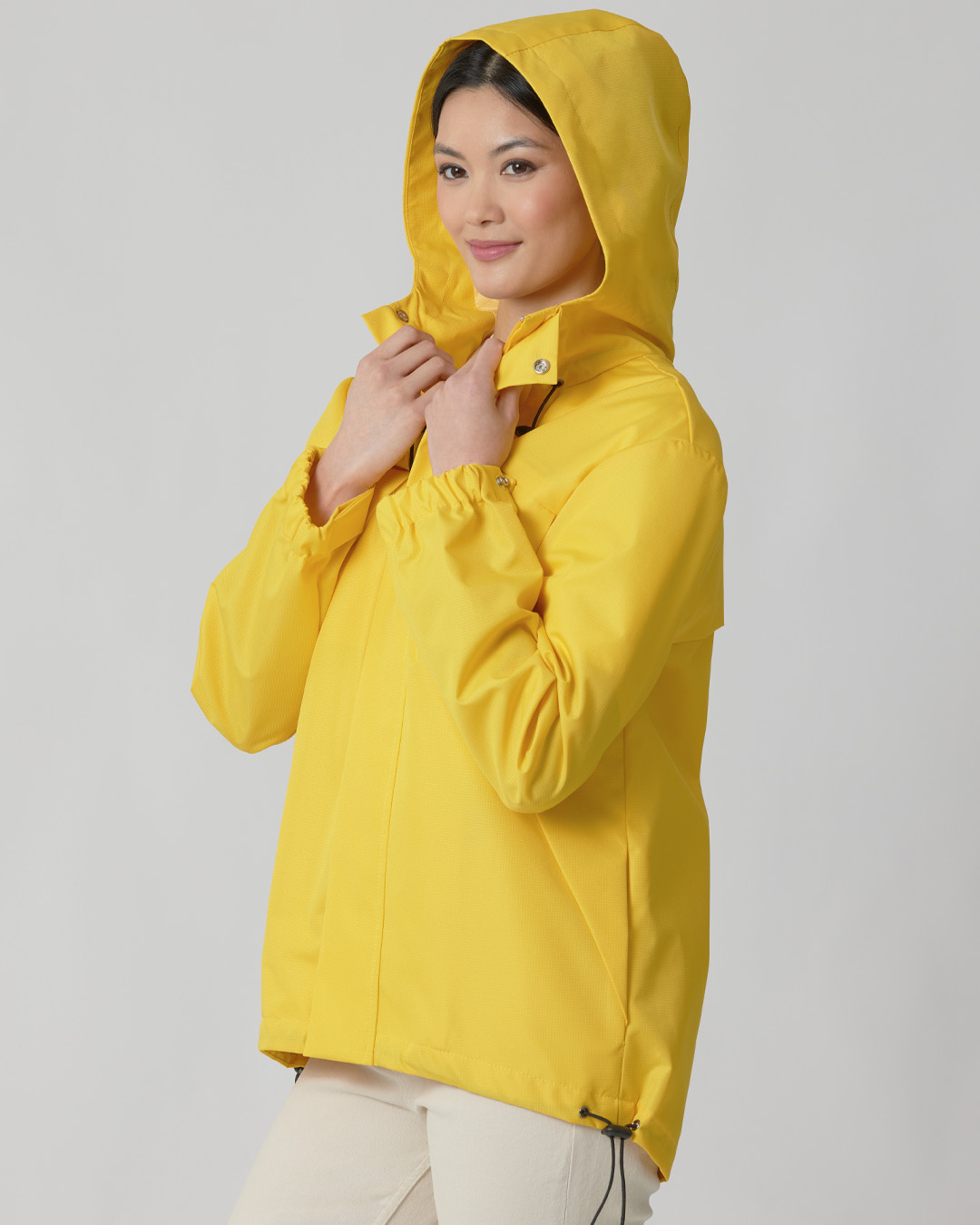 A woman wearing a yellow rain jacket with a hood.
