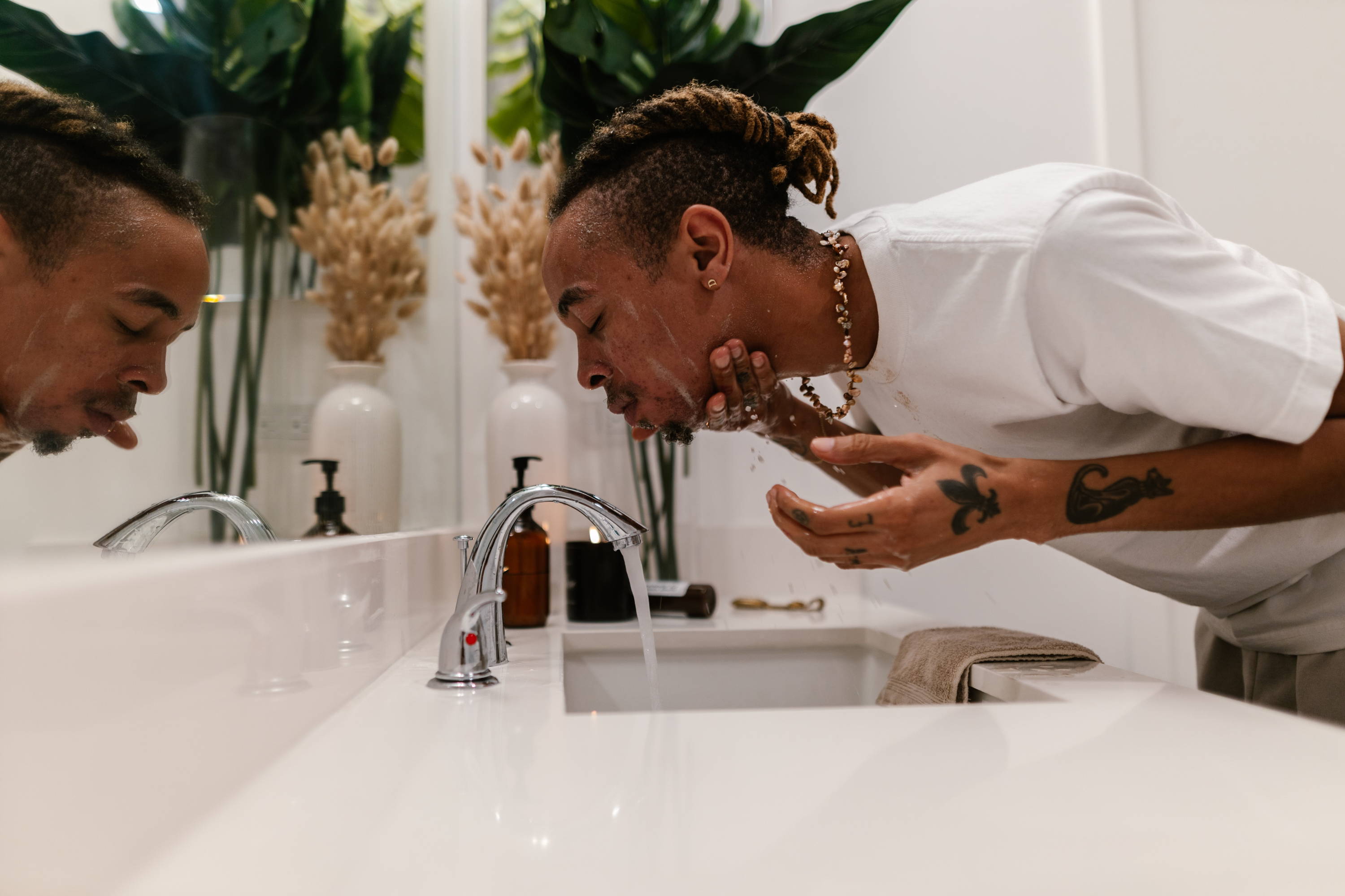 man washing his face in front of a mirror