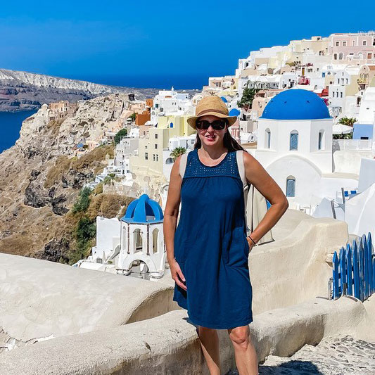 Ambassador Tamara wearing blue Aventura dress overlooking Santorini Greece.