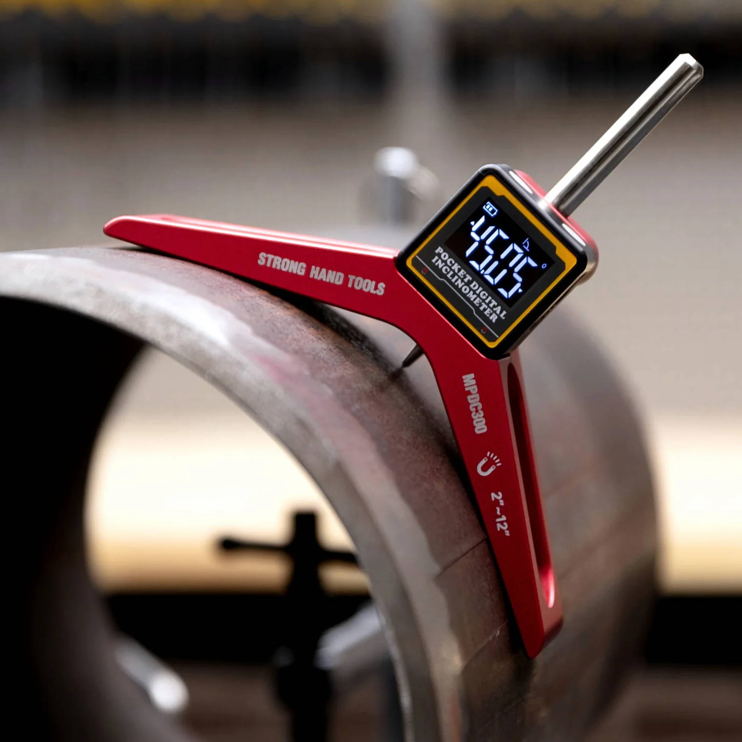 A red measuring tool placed on a metal pipe in a workshop.