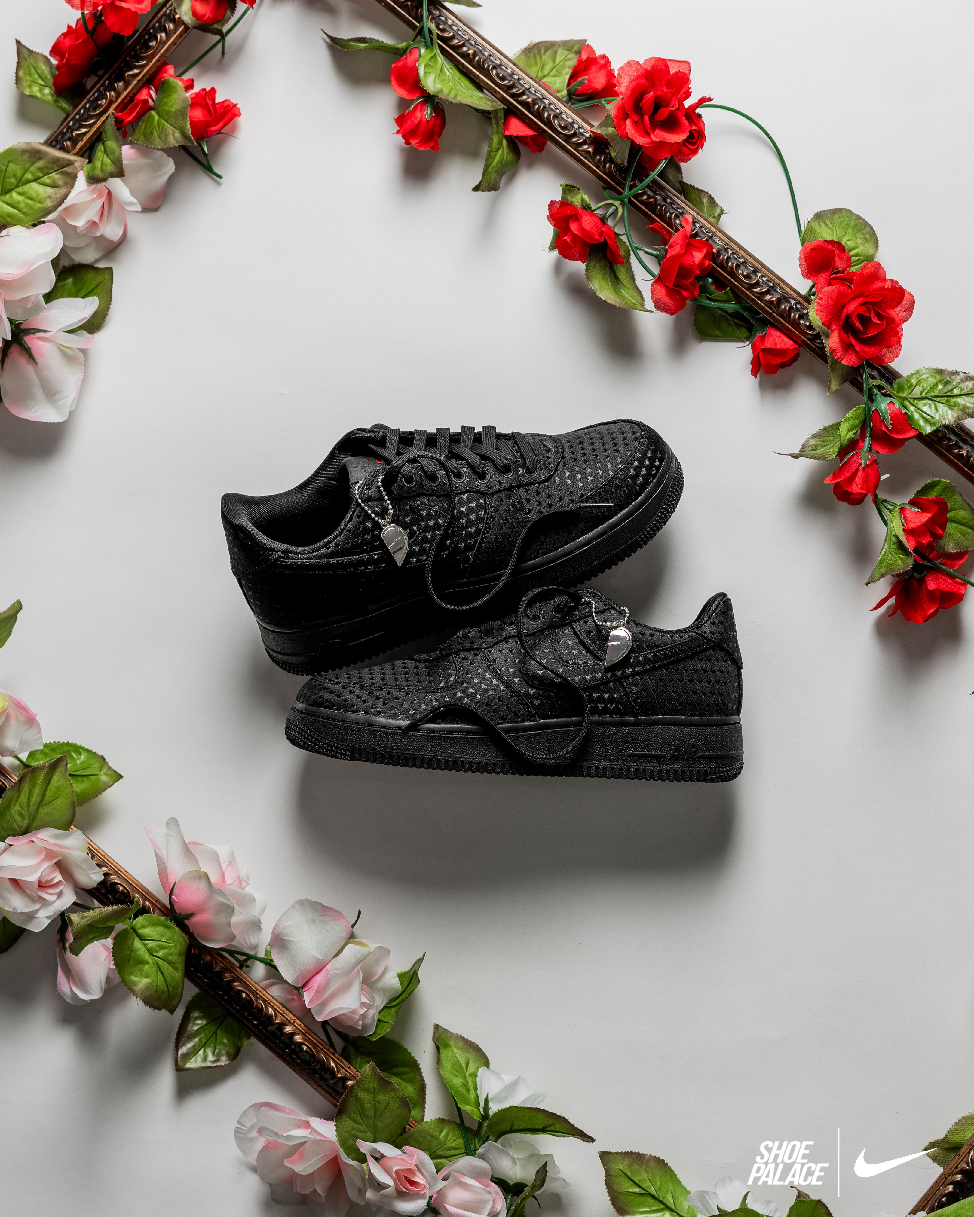 Black sneakers surrounded by flowers on a white background.