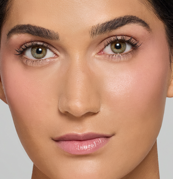 Close-up of a person’s face with green eyes and natural makeup.