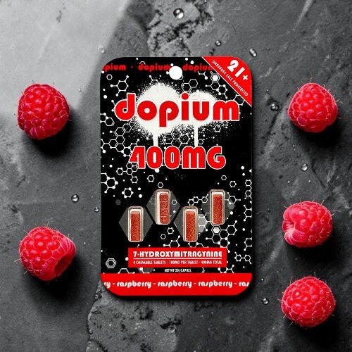 Package of dopium 400mg dietary supplement with raspberries on a dark surface.