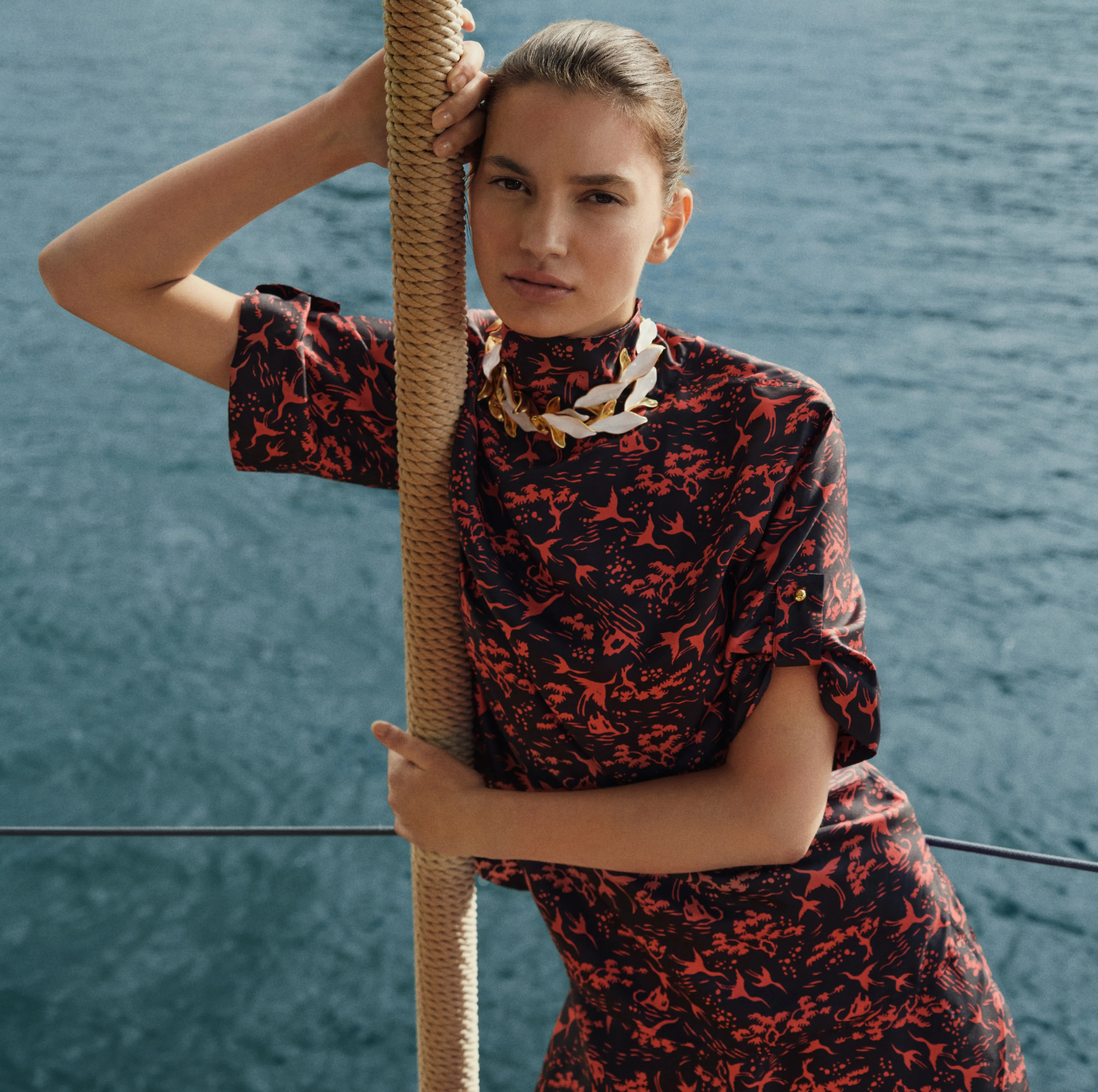 Model in stylish dress posing by the water.