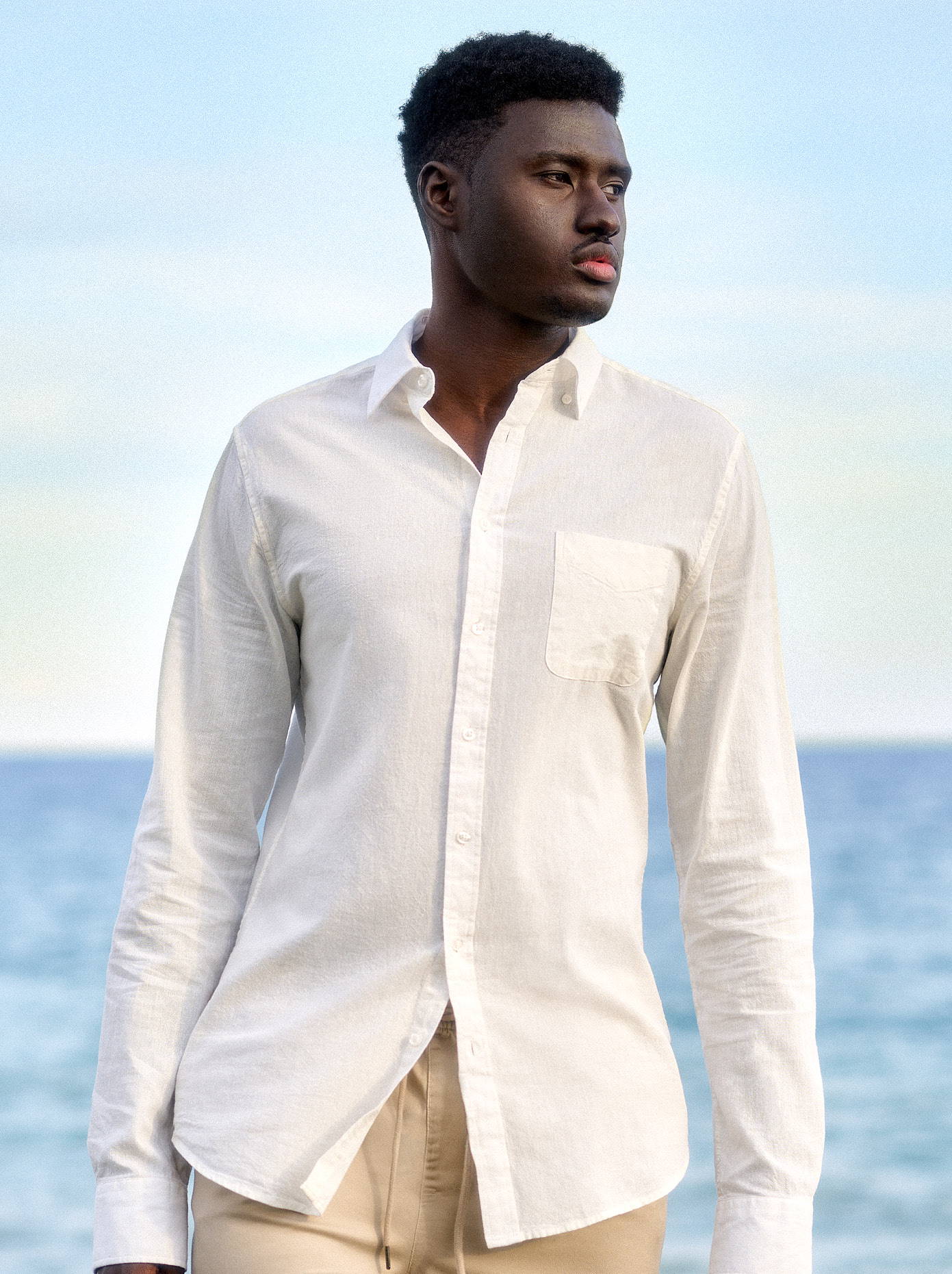 Tall man wearing a white linen shirt by the water