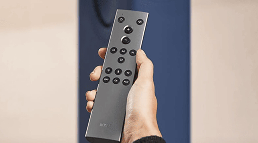A hand holding a modern remote control against a simple background.