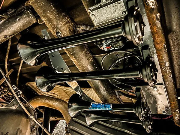 Close-up underside view of black train horn bells and mounting bracket on Justin's 2017 Chevrolet 2500HD, install photo 3
