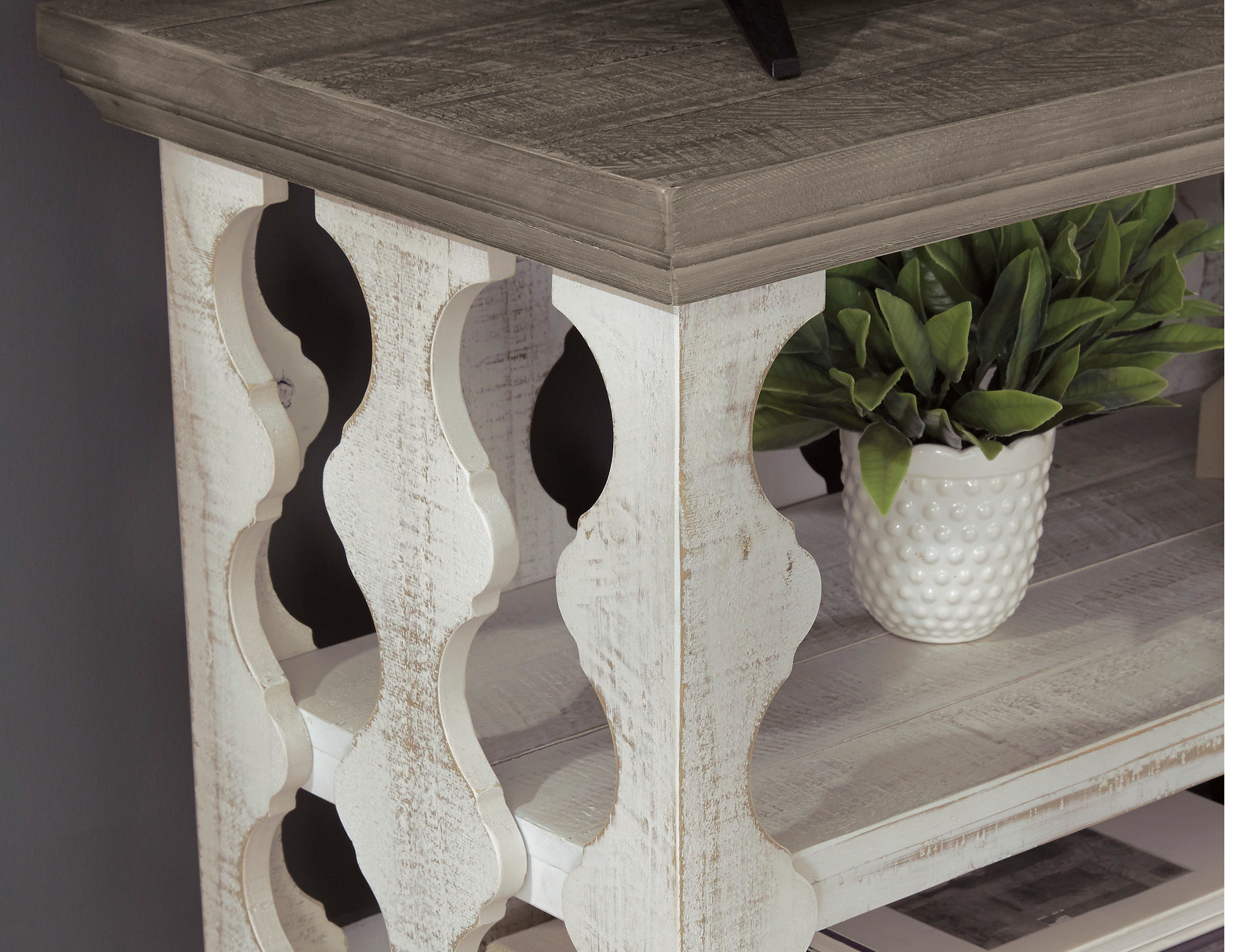 Decorative wooden console table with open shelves and a potted plant.