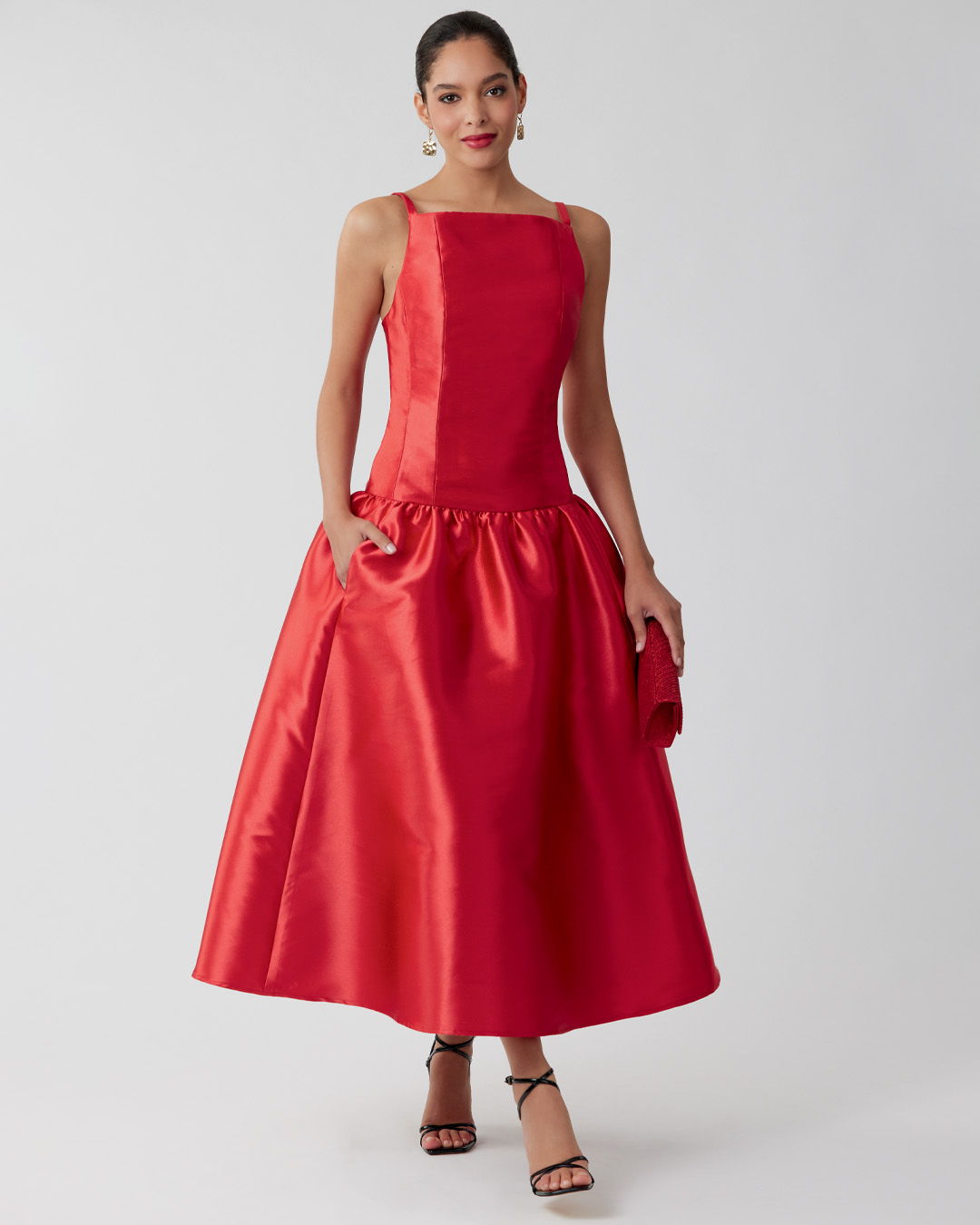 Woman in a red dress with a flared skirt, standing elegantly.