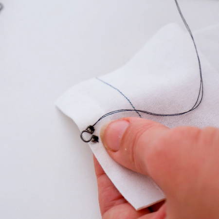 The eye of the hook and eye closure attached to a piece of fabric
