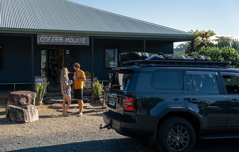 Two people getting coffee in front of their 4WD with roof rack platform