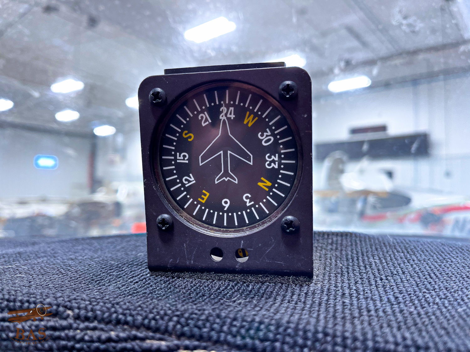 Aircraft instrument displaying directional heading in a hangar setting.