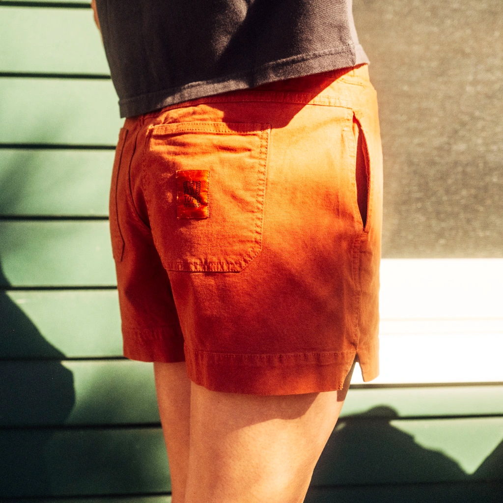 Person wearing orange shorts standing against a green wall.